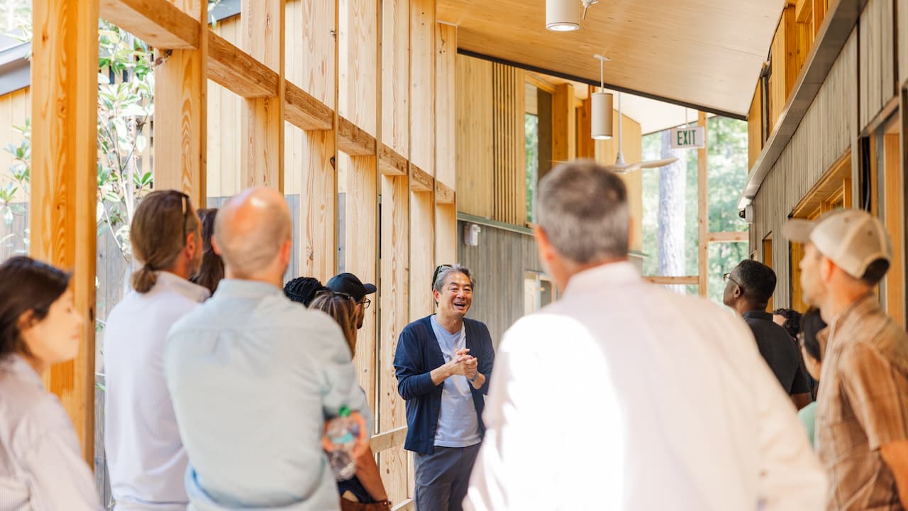 man talking to an audience inside a wood building