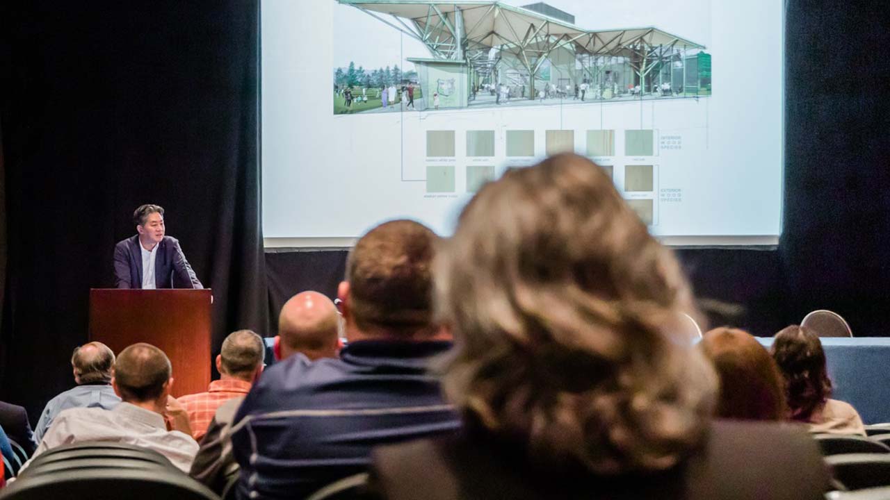 A man speaks in auditorium with people.